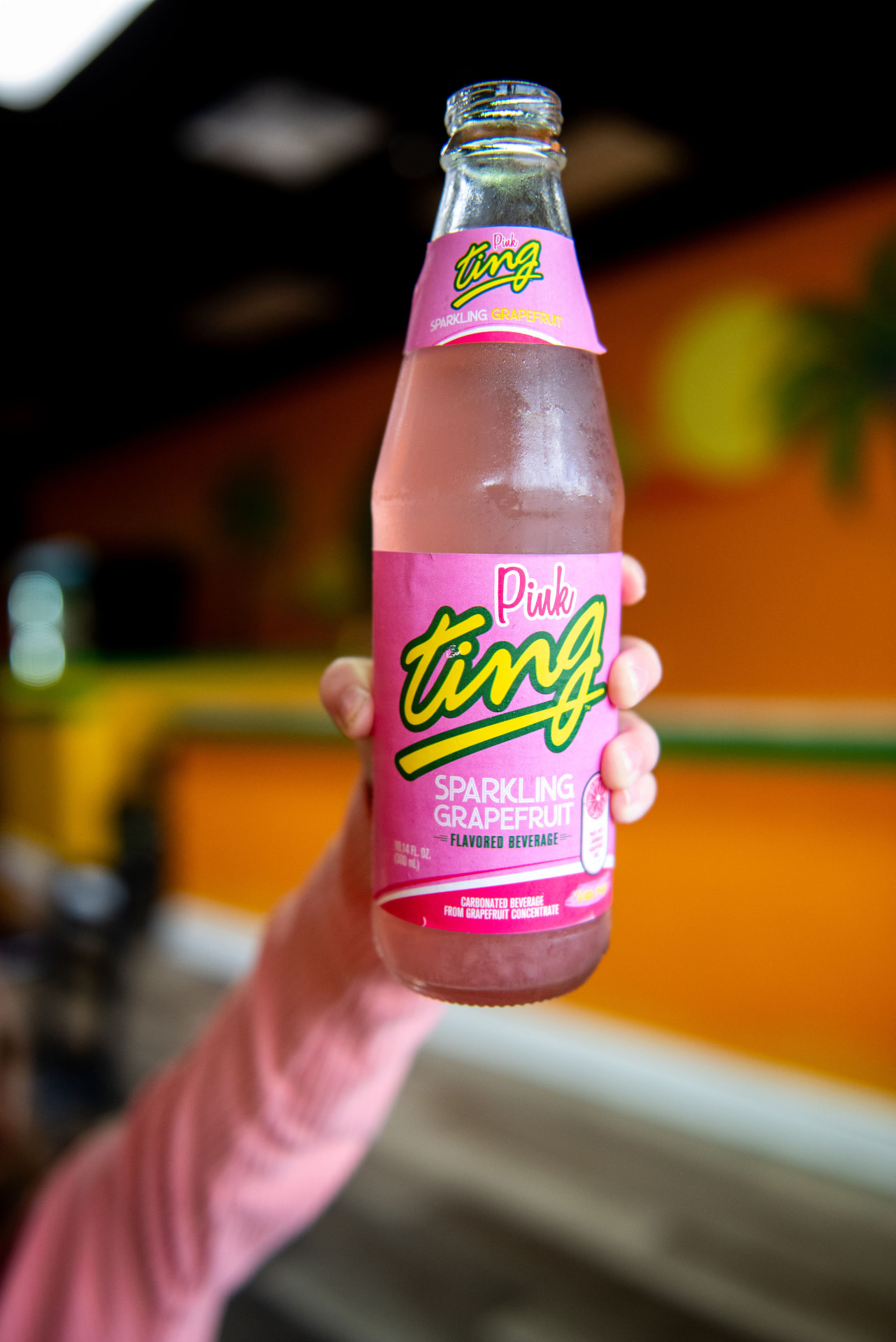An ice-cold bottle of Pink Ting sparkling grapefruit soda held up inside Mama Spice